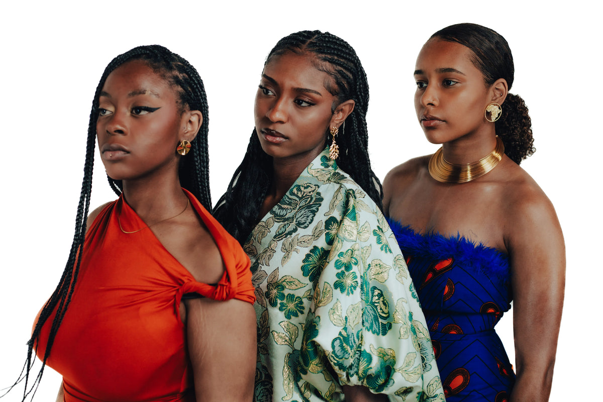 Three women wearing colourful outfits and Cameroon Jewels jewelry against a white background