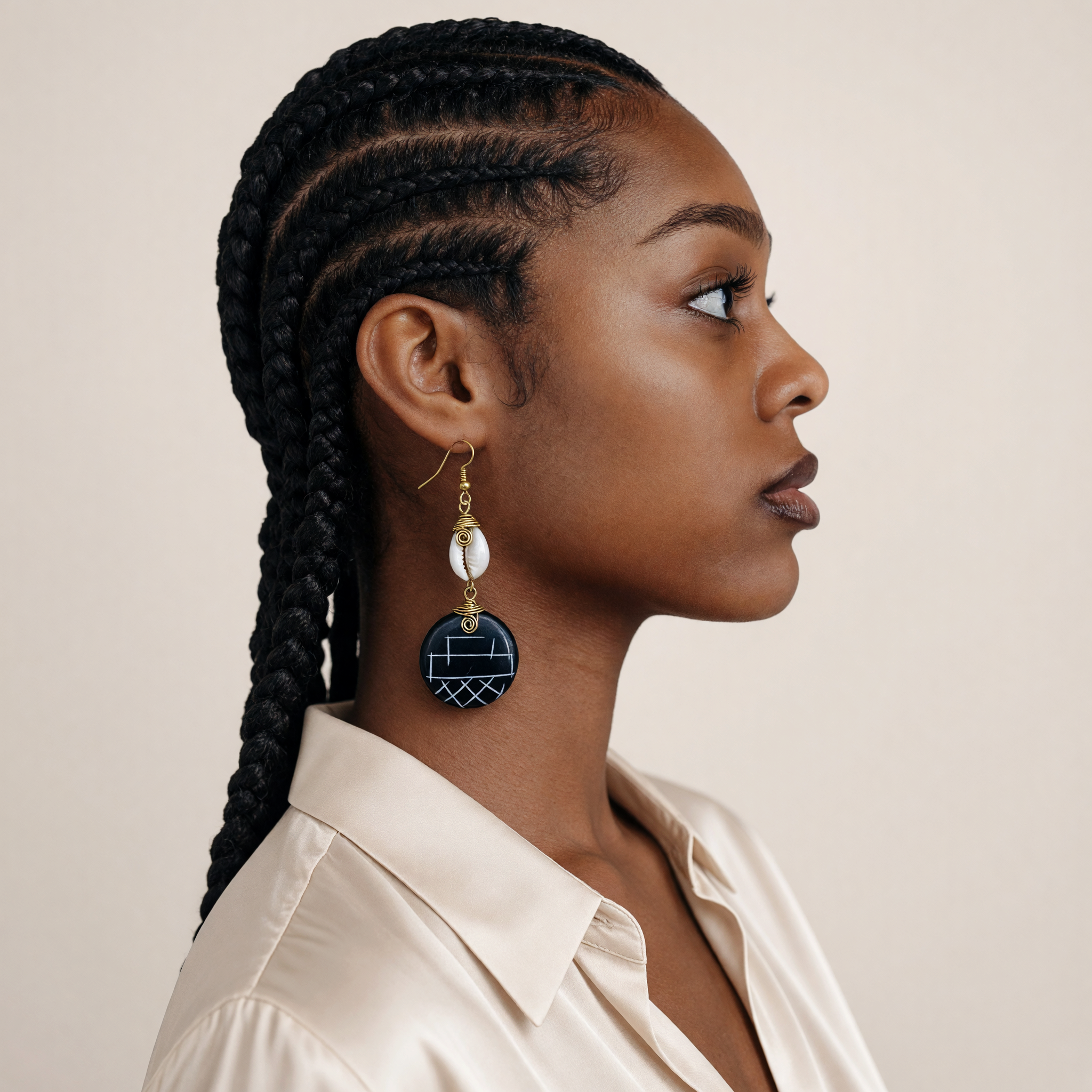 CameroonJewels Bois de Mère earrings featuring hand-carved painted wood, brass wire, and a cowry shell on a model.