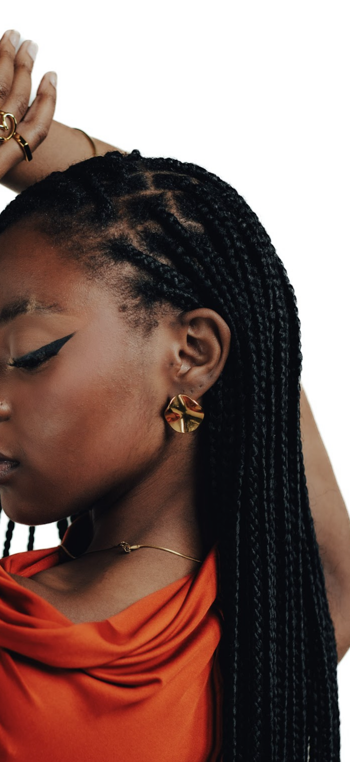 CameroonJewels Cercle d'Or 18K gold-plated steel hoop earring worn by a woman with braided hair and orange top