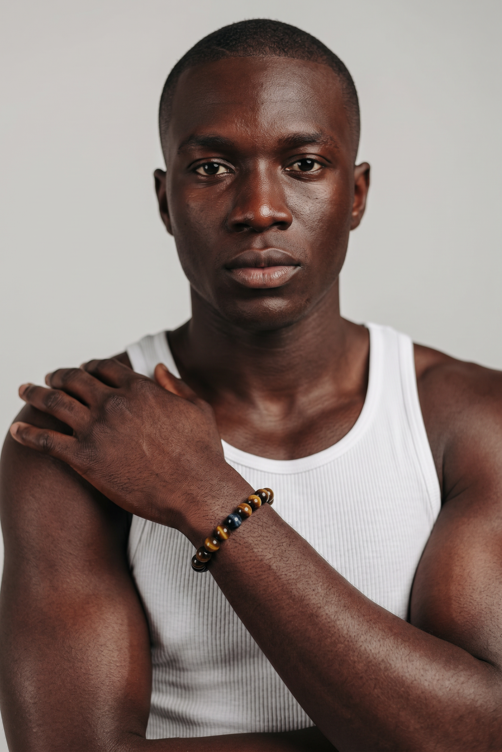 CameroonJewels Oeil du Tigre natural tiger eye beaded bracelet worn on the wrist of a man in a white tank top